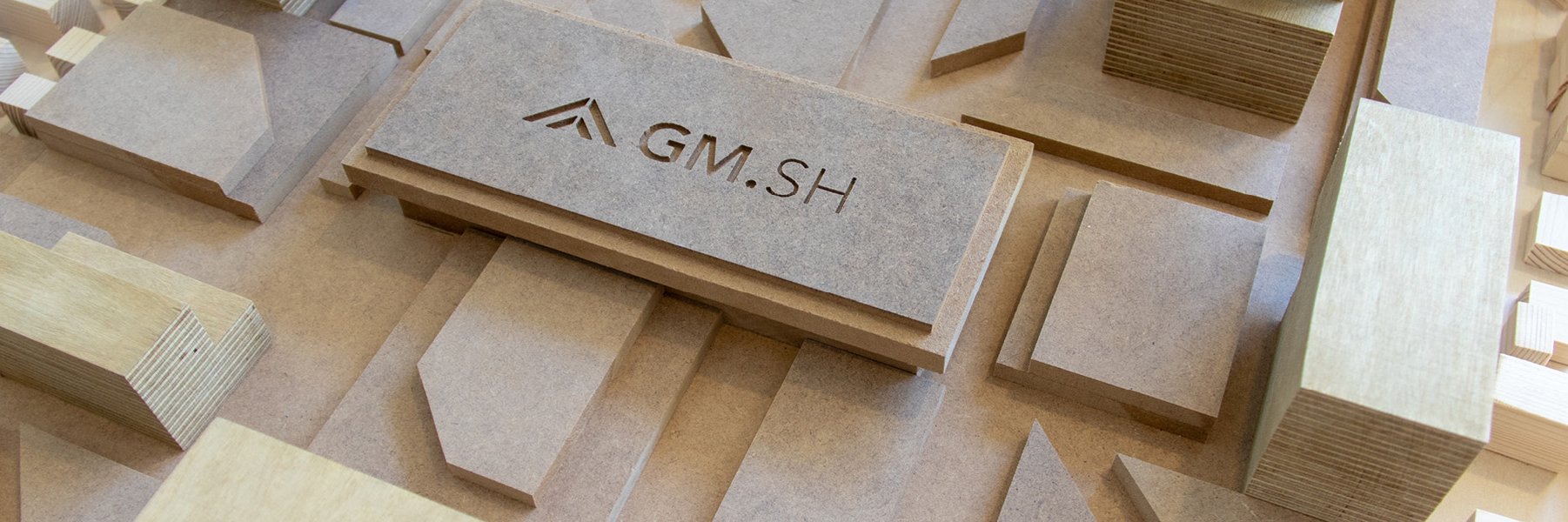 Vogelperspektive von einem Holz-Modell, es zeigt Gebäude und auf einem Holzklotz ist das GMSH-Logo zu sehen. 