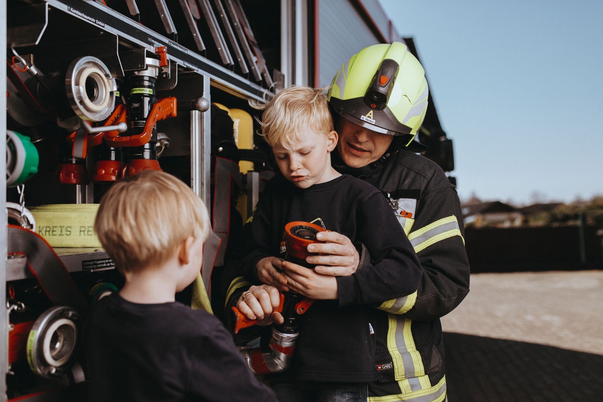 Andreas Herbst zeigt seinen Kindern etwas am Feuerwehrwagen. 