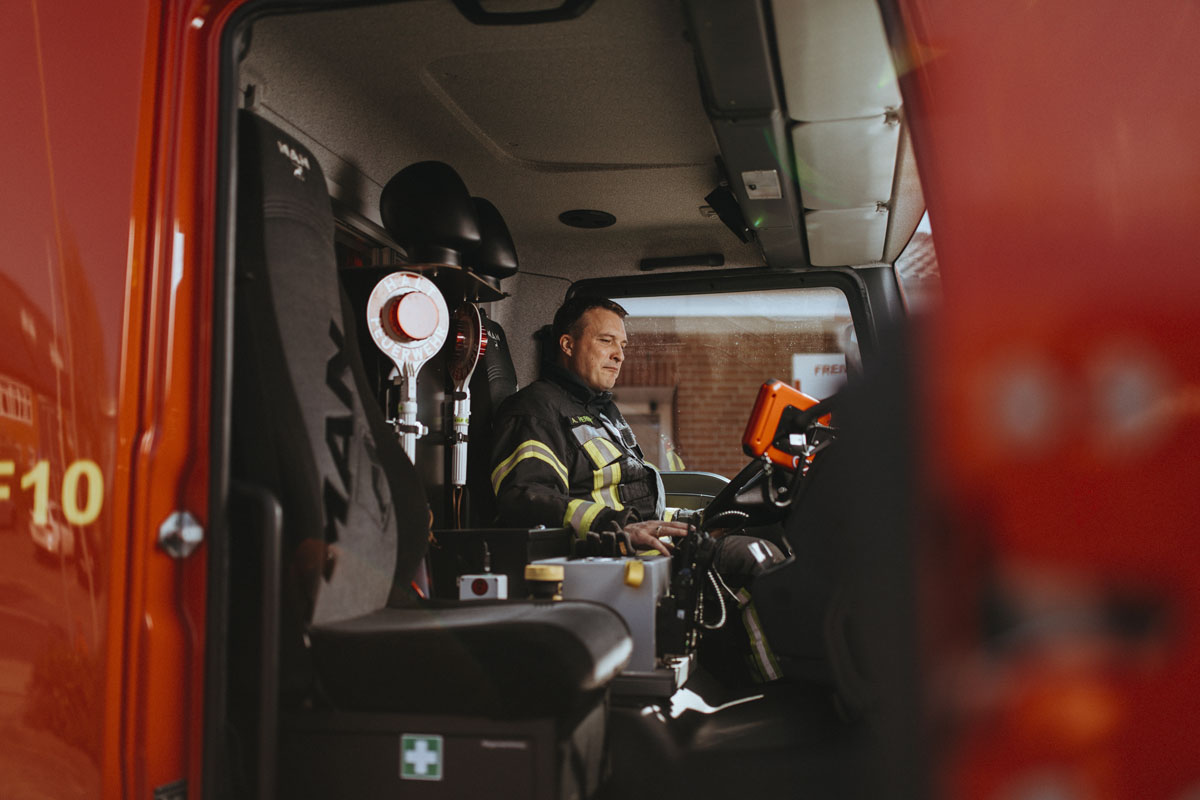 Blick in die Fahrerkabine eines Feuerwehrautos. Andreas Herbst sitzt am Steuer. 